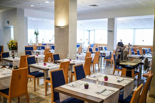 una sala da pranzo con tavoli e sedie bianchi di Hotel Bella Venezia Mare a Lignano Sabbiadoro