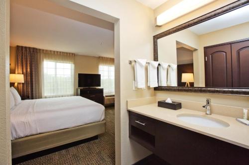 a bathroom with a bed and a sink and a mirror at Staybridge Suites Austin South Interstate Hwy 35 by IHG in Austin