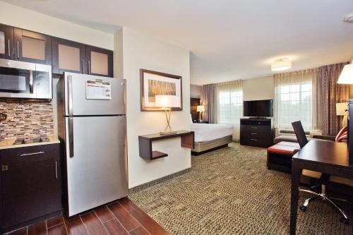 a hotel room with a refrigerator and a bedroom at Staybridge Suites Austin South Interstate Hwy 35, an IHG Hotel in Austin