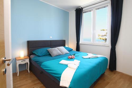 a bedroom with a blue bed with towels on it at Apartma San Simon s pogledom na morje - San Simon Sea View Apartment LL in Izola