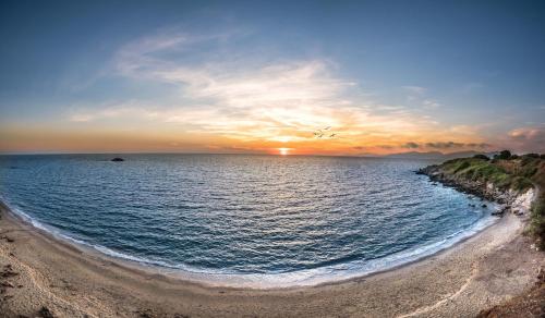 ミティカスにあるDionisos Hotelの砂浜の海に沈む夕日