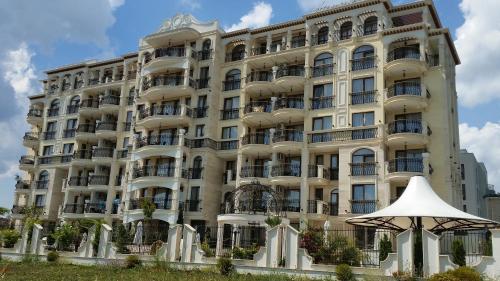 a large white building with an umbrella in front of it at Harmony Suites Apartment in Sveti Vlas