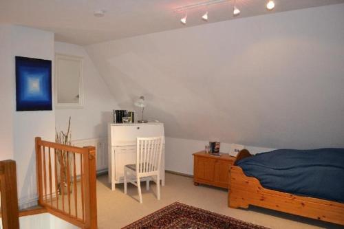Schlafzimmer mit einem Bett, einem Tisch und einem Kühlschrank in der Unterkunft Appartement Beisel unter Reet in Garding
