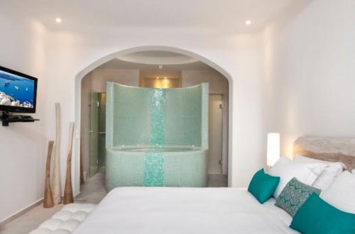 a bedroom with a large bath tub with a bed at Allure Suites in Firostefani