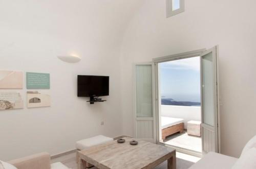 a white living room with a table and a tv at Allure Suites in Firostefani
