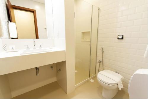 y baño con aseo, lavabo y ducha. en Livramento Palace Hotel, en Vitória da Conquista