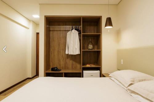 um quarto com uma cama branca e um closet em Livramento Palace Hotel em Vitória da Conquista