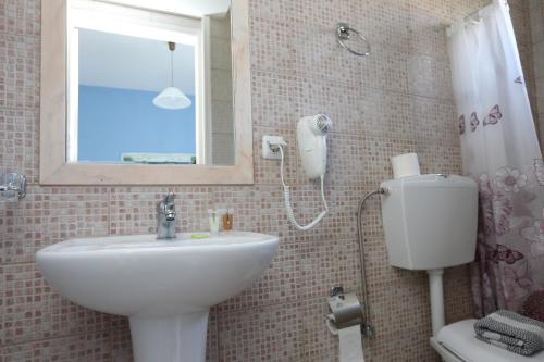 a bathroom with a sink and a toilet and a mirror at Hotel Kastro in Skiathos Town