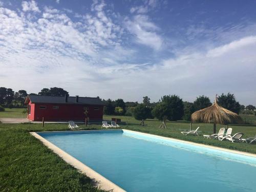 a swimming pool with chairs and a red barn at Cabanas El Yarquen in Sierra de los Padres