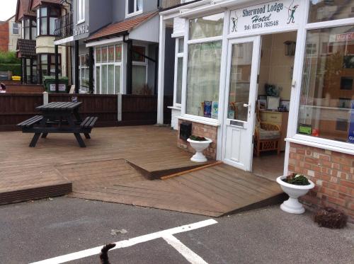 a store front with a bench and a wooden deck at Sherwood Lodge in Skegness