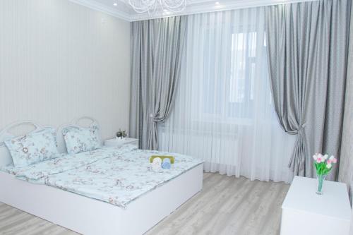 een witte slaapkamer met een groot bed en gordijnen bij Luxury apartment Promenade Expo in Astana