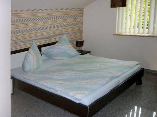 Bett mit blauer Bettwäsche und Kissen in einem Zimmer in der Unterkunft Ferienwohnung Dräger in Mardorf