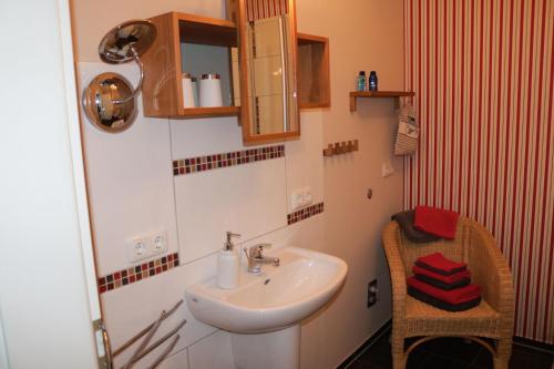 ein Badezimmer mit einem Waschbecken, einem Spiegel und einem Stuhl in der Unterkunft Ferienwohnung "Abendröte" in Lüdersburg