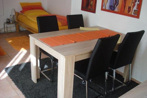 un tavolo in legno con sedie nere e un letto di 2-Zimmer-Appartement-Seerose a Pliezhausen