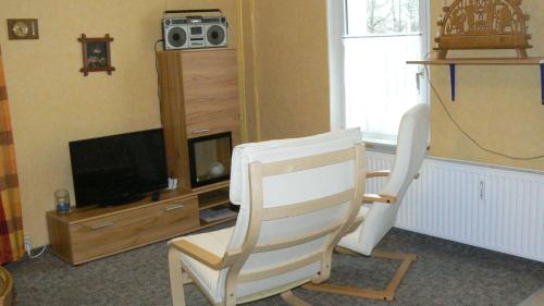 a living room with a chair and a television at Zimmervermietung-Heide-Fiege in Hartmannsdorf