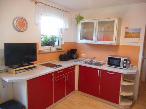 eine Küche mit roten Schränken, einer Spüle und einer Mikrowelle in der Unterkunft Rothers Ferienwohnung in Annaberg-Buchholz
