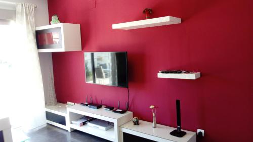 een rode muur met witte planken en een tv erop bij Apartamento Puerto Real in Torremolinos