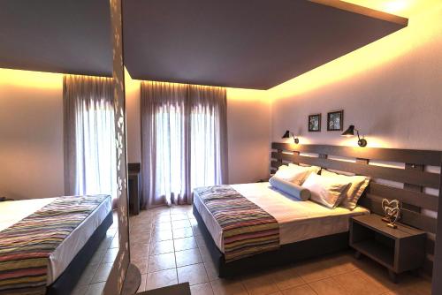 a bedroom with two beds and a large window at Aliston Hotel Studios, Adults Only in Skala Potamias