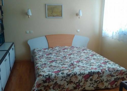 a bedroom with a bed with a floral bedspread at Fenix Rooms in Arbanasi