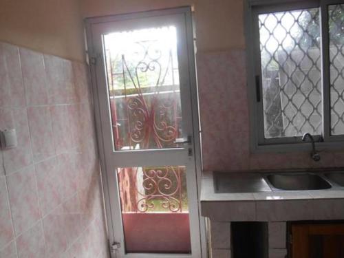 a door to a kitchen with a window and a sink at Rose Garden Apartments in Limbe