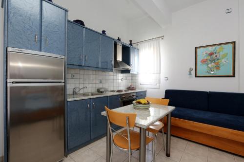 Aristeides - Moscha Apartments في بلاتيس ييالوس سيفنوس: مطبخ مع الدواليب الزرقاء وطاولة مع صحن من الفواكه عليها