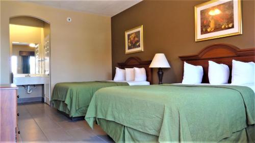 a hotel room with two beds with green sheets at La Copa Inn in McAllen