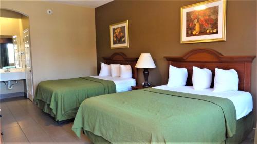 a hotel room with two beds with green sheets at La Copa Inn in McAllen