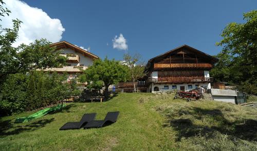 a house on a hill with benches in front of it at Rumpelehof in Villandro