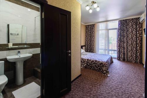 1 cama y baño con lavabo y aseo. en Hotel Seven, en Lazarevskoye