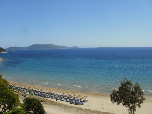 a beach with a bunch of chairs and the ocean at Charly Point Villa in Methoni