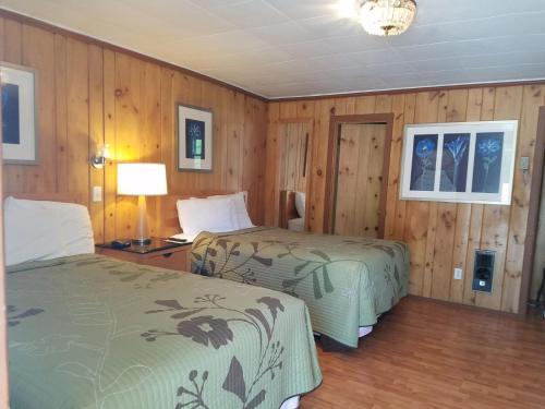 two beds in a room with wood paneling at Seven Dwarfs Cabins - Brown Cabins in Lake George