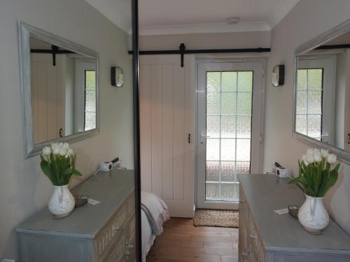 a bathroom with a mirror and a sink with flowers on it at Church Combe - Petworth West Sussex in Petworth