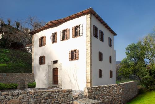 a white house with a stone wall at Mountain's Secret in Mouresi