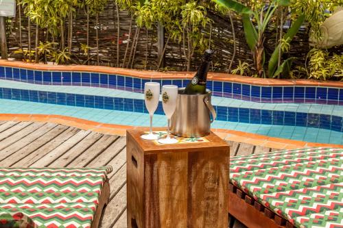 a bottle of wine in a bucket on a table next to a pool at Pousada Bahia Brasil in Morro de São Paulo