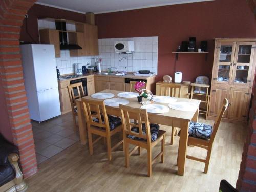 a kitchen with a table and chairs and a refrigerator at Ferienhaeuser-MoJe-1 in Dornum