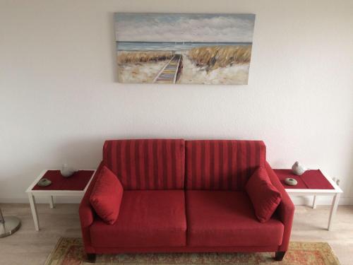 ヴェスターラントにあるFerienwohnung-Sylt-Studioの壁画のあるリビングルームの赤いソファ