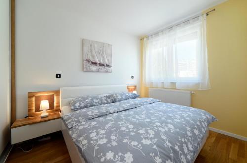 a bedroom with a bed with a blue comforter and a window at Precko7NEW in Zagreb