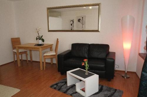 ein Wohnzimmer mit einem schwarzen Sofa und einem Tisch in der Unterkunft Ferienwohnung - Konvikt Nr. 3 in Freiburg im Breisgau