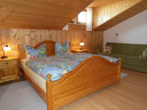 een slaapkamer met een houten bed en een bank bij Klausgupf in Neureichenau