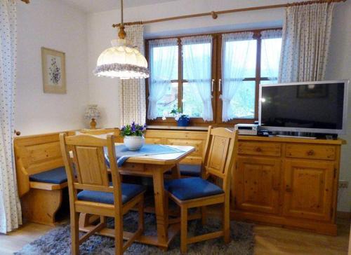 ein Esszimmer mit einem Tisch mit Stühlen und einem TV in der Unterkunft Landhaus Haid Fewo Enzian in Schönau am Königssee