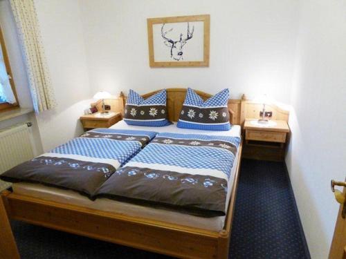 ein Schlafzimmer mit einem Holzbett mit blauen Kissen in der Unterkunft Landhaus Haid Fewo Enzian in Schönau am Königssee