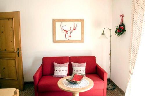 a red couch with pillows and a table in a room at Landhaus-Haid-Fewo-Edelweiss in Schönau am Königssee