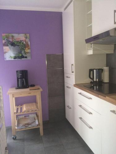 eine Küche mit weißen Schränken und einer lila Wand in der Unterkunft Ferienwohnung Köhler in Altreichenau