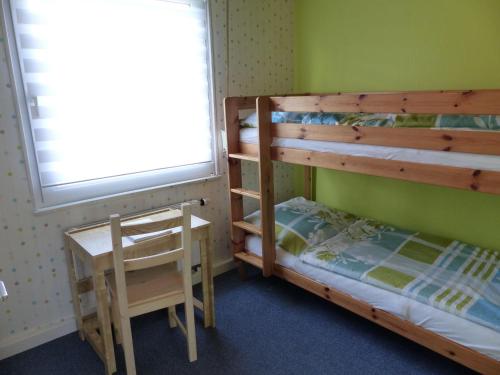 ブルハーフェにあるFerienhaus-Mellumringのベッドルーム1室(二段ベッド1組、デスク、椅子付)