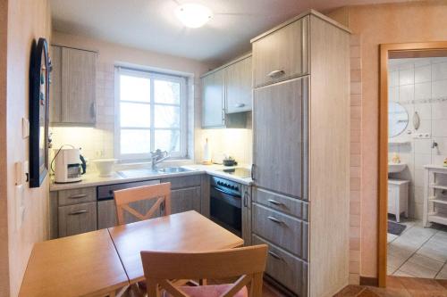 cocina con mesa de madera y cocina con nevera en Ferienhaus Jan, en Nordstrand