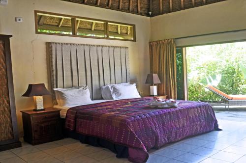 a bedroom with a bed with a cat laying on it at Bayside Bungalows in Candidasa