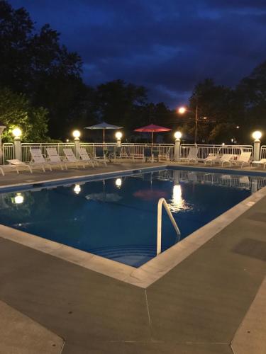 a swimming pool at night with chairs and umbrellas at Cape Harbor Motor Inn in Cape May