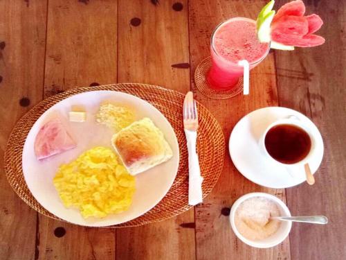 a table with a plate of eggs and a cup of coffee at Hotel Uyah Amed Spa Resort in Amed