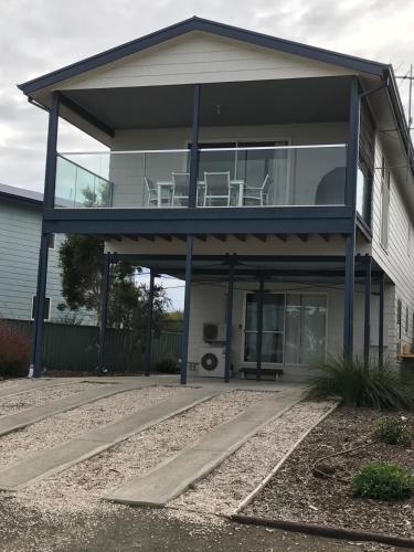 a house with a balcony with two chairs in it at Bayview Beach House Apartment No 2 in Kingscote
