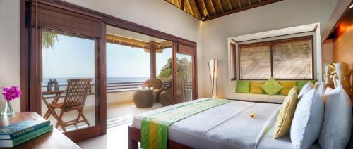 a bedroom with a bed with a view of the ocean at Palm Garden Amed Beach & Spa Resort Bali in Amed